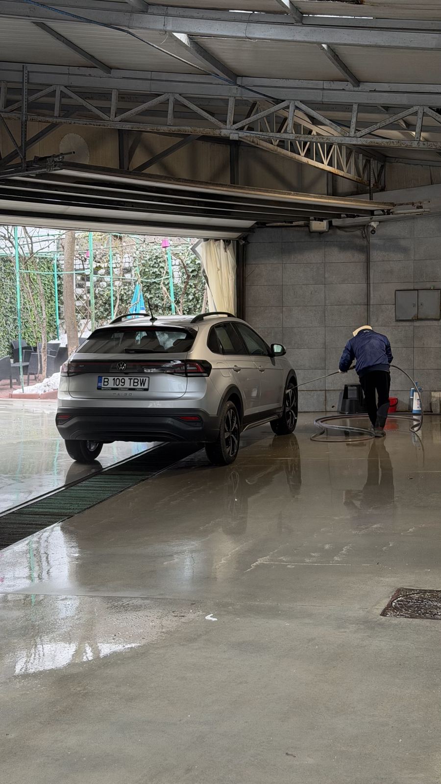Boxa de spălare acoperită, un angajat spală un SUV alb